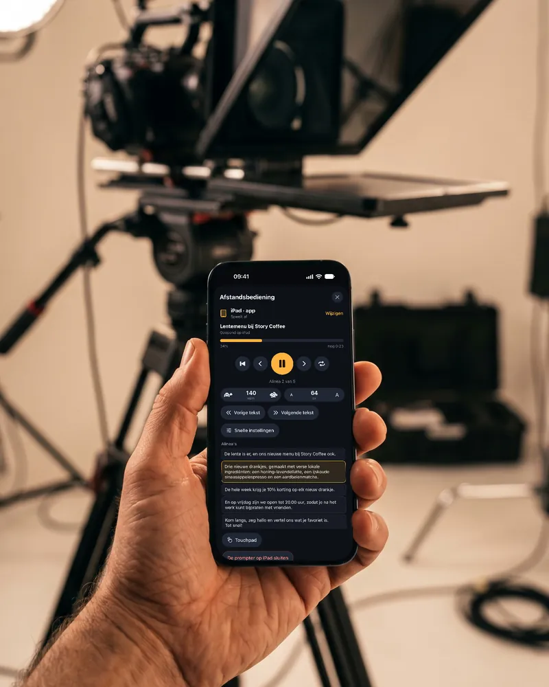 Een videomaker houdt een iPhone vast met de afstandsbediening van EasyPrompter, met de camerateleprompter erachter.