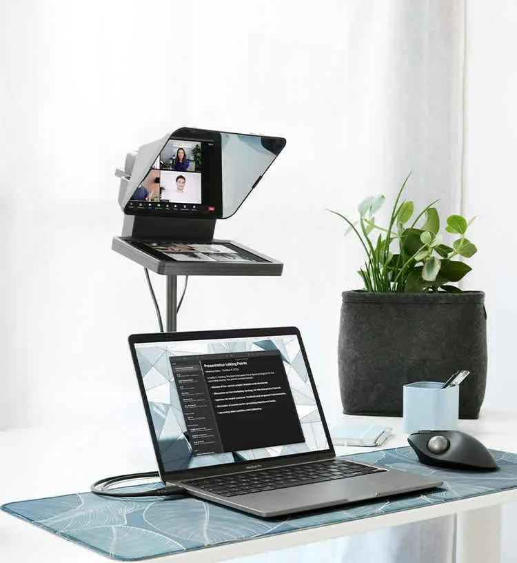 The Elgato Prompter on a desk stand above a laptop, showing a video call on its screen